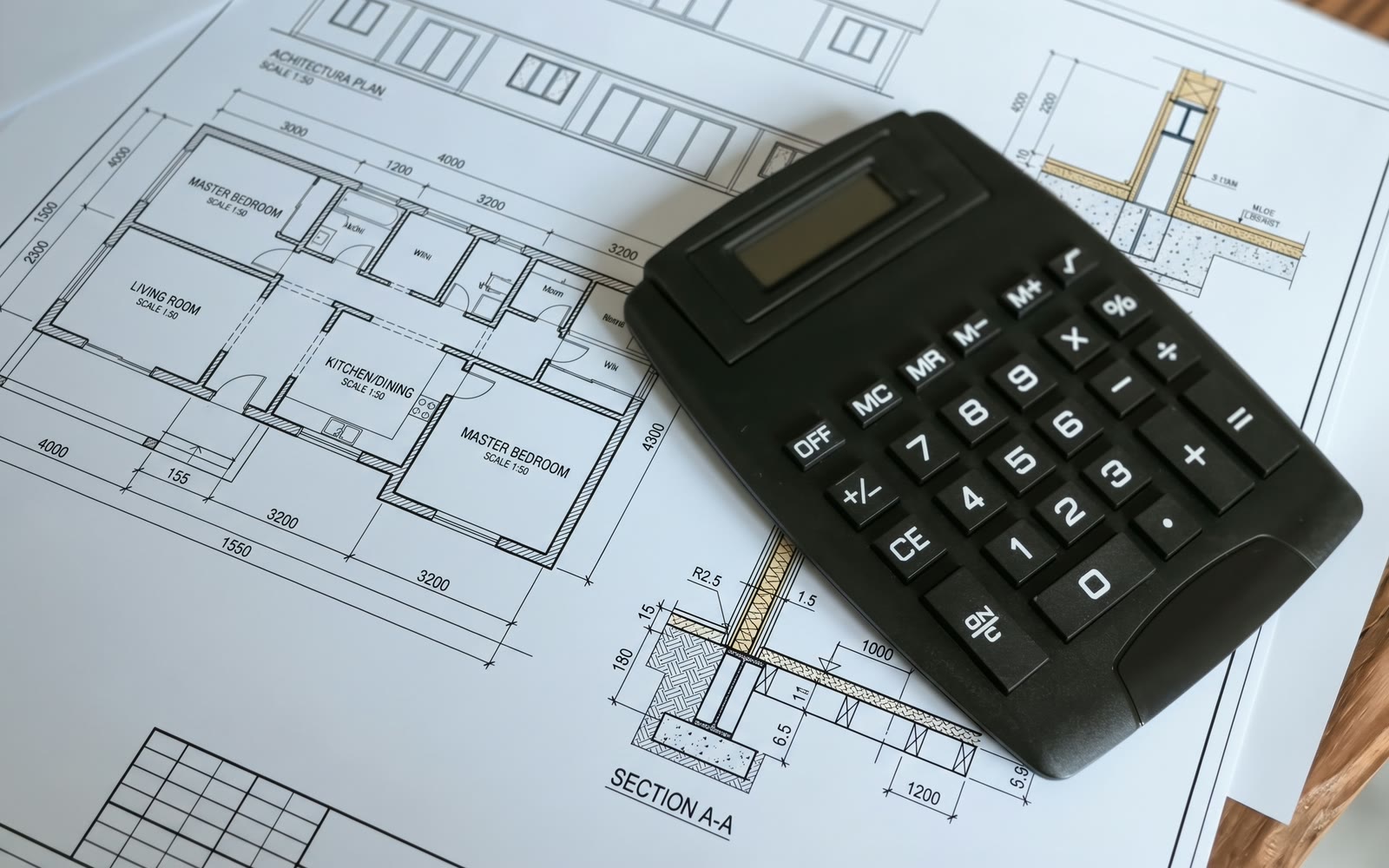 A calculator resting on a floor plan and wall section