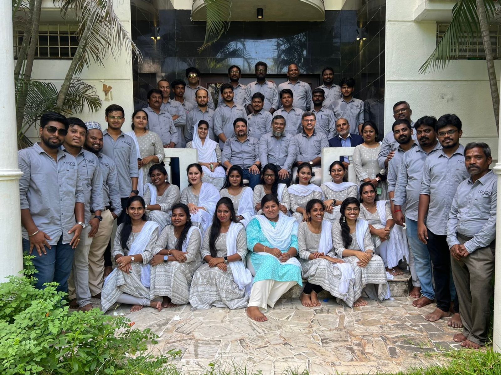 The Rayan Architects studio gathered on the front steps of the office in grey studio shirts